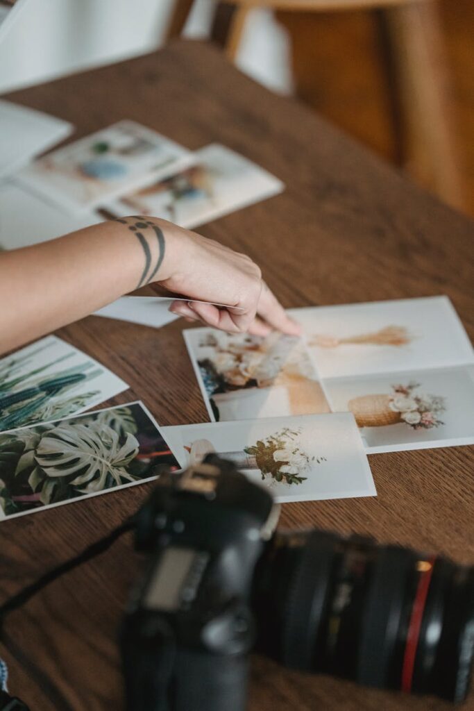 crop anonymous person pointing at photos scattered on table
